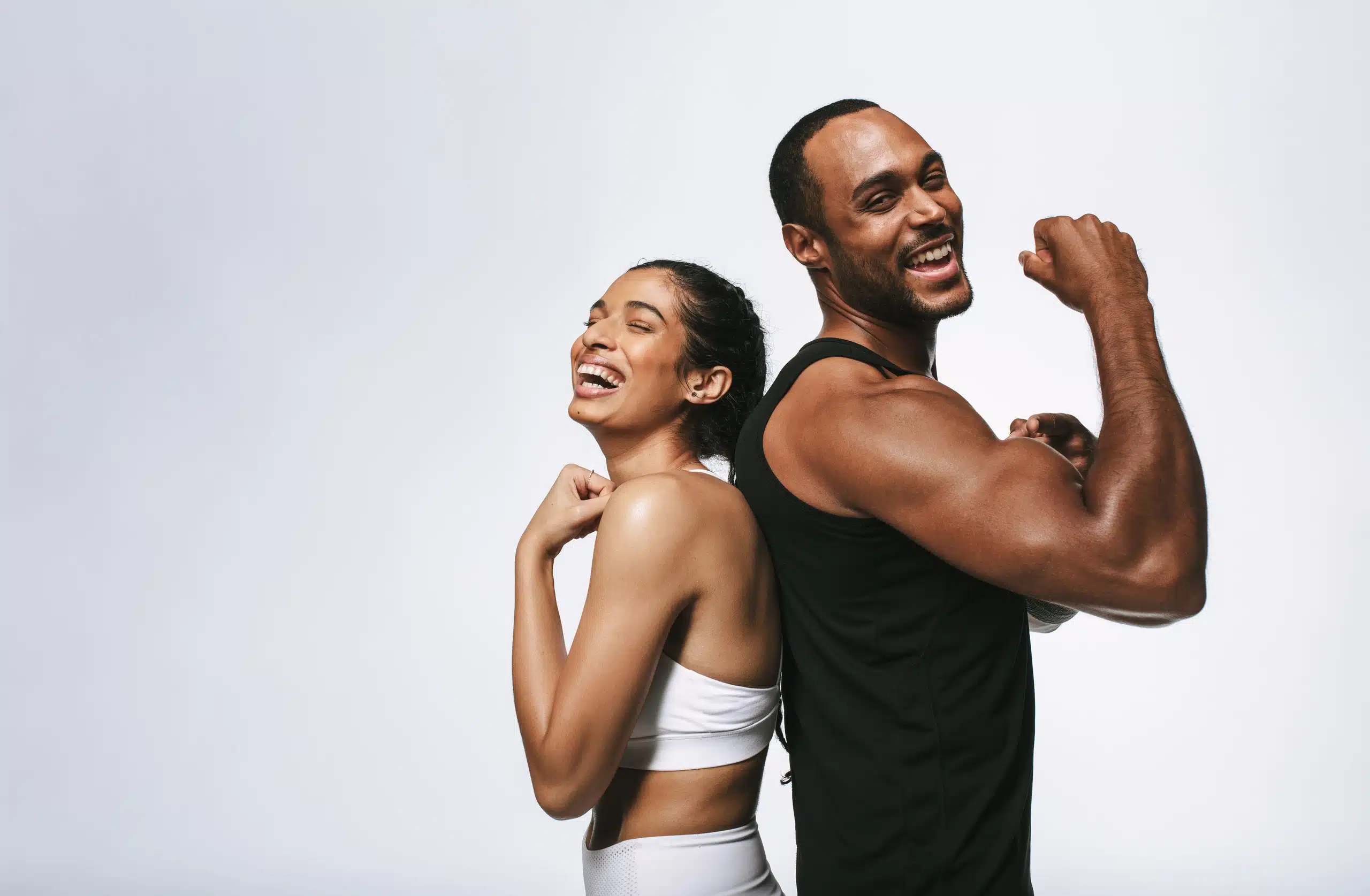 Fit and happy man and woman standing back-to-back, showing toned bodies and confidence, representing results of Emsculpt NEO body contouring treatment at Seashore MD in Little Silver, NJ.